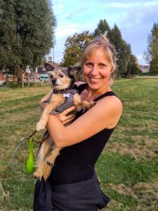Dog walker Steph holds a small dog in her arms in a field in Cambridge.