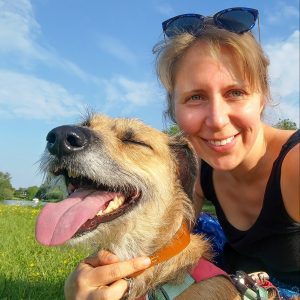 A happy lurcher with her tongue out poses with Steph.