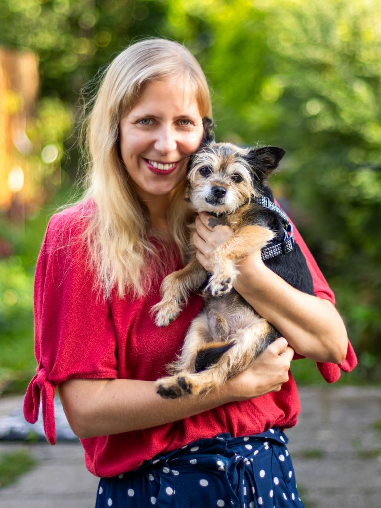 A woman happily holds an adorable dog - a yorkie chihuahua mix - in her arms.